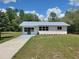 Charming single-story home with a metal roof, tidy lawn, and freshly painted long driveway at 23177 Sw Beach Blvd, Dunnellon, FL 34431