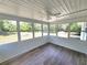 Bright sunroom with wood-look floors, a ceiling fan, and multiple windows offering serene views of the backyard at 23177 Sw Beach Blvd, Dunnellon, FL 34431