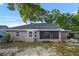 Rear exterior showcasing a patio, screened porch, and fenced yard shaded by mature trees at 4246 Ne 32Nd Cir, Ocala, FL 34479