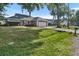View of the front exterior featuring a large lawn, mature trees, and a two car garage at 4246 Ne 32Nd Cir, Ocala, FL 34479