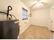 Bright laundry room with neutral tile flooring, window with blinds, and modern water heater at 4785 Ne 28Th Ter, Ocala, FL 34479
