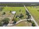 Aerial view of property featuring lush green pastures, a riding arena, and mature trees at 5363 Nw 153Rd Ct, Morriston, FL 32668