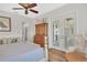 Bright primary bedroom with ceiling fan, French doors, a dresser, a comfortable chair and wood floors at 5363 Nw 153Rd Ct, Morriston, FL 32668