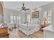 Bright primary bedroom with hardwood floors, white trim, plantation shutters, ceiling fan, and a seating area at 5363 Nw 153Rd Ct, Morriston, FL 32668