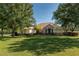 Charming single-story home featuring a stone facade, manicured lawn, and mature trees at 5363 Nw 153Rd Ct, Morriston, FL 32668