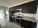 Modern kitchen with dark cabinets, stainless steel appliances, and a granite countertop at 593 Marion Oaks Trl, Ocala, FL 34473
