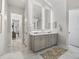 Bright bathroom featuring double vanity with illuminated mirrors and marble flooring at 7161 Ne 22Nd Court Rd, Ocala, FL 34479