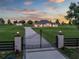 Gated estate showcasing a long driveway leading to an elegant home at sunset at 7161 Ne 22Nd Court Rd, Ocala, FL 34479