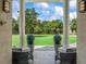 Covered patio showcasing two chairs, potted plants, and picturesque views of the expansive green lawn and mature trees at 7161 Ne 22Nd Court Rd, Ocala, FL 34479