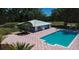 Community pool with a building, surrounded by a patterned brick patio and lush green landscaping at 8221 Sw 217 Ct, Dunnellon, FL 34431