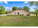 Back side of home with an enclosed porch, white fence, mature trees and lawn at 8221 Sw 217 Ct, Dunnellon, FL 34431
