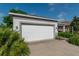 Attached two-car garage with a white door, neutral exterior paint, and tropical foliage at 8546 Sw 79Th Ave, Ocala, FL 34476