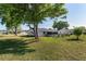 Backyard with mature trees, green grass, and a white home featuring a screened lanai at 8851 Sw 116Th Street Rd, Ocala, FL 34481
