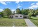 A cozy single-story home with a covered carport surrounded by a lush green lawn and mature trees at 8954 Sw 104Th Ln, Ocala, FL 34481