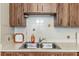 A kitchen sink with wood cabinets and tiled backsplash, showcasing a traditional design at 8954 Sw 104Th Ln, Ocala, FL 34481