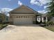 Charming single-story home featuring a two-car garage, tan stucco, and stone accents on a sunny day at 9764 Sw 100Th Avenue Rd, Ocala, FL 34481