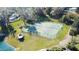Aerial view of a community tennis court with lights, green surface, and a gazebo with a pond nearby at 0000 Se 17Th Ct, Ocala, FL 34471