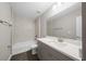 Bright bathroom featuring a tub with tile surround, quartz countertop, wood-look flooring, and modern fixtures at 10435 Se 125 Ln, Belleview, FL 34420