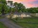 Charming single-story home with a manicured lawn, complemented by the light of a vibrant sunset at 13897 W Highway 328, Ocala, FL 34482