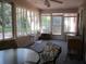 The sunroom has many windows, a ceiling fan, and a table and chairs at 14244 Sw 115Th Cir, Dunnellon, FL 34432