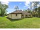 View of the house's backyard featuring green grass, a covered patio and mature trees in the background at 19939 Sw 96Th Pl, Dunnellon, FL 34432