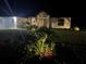 Night view of a house with landscape lighting, highlighting the well-maintained lawn and inviting front facade at 19939 Sw 96Th Pl, Dunnellon, FL 34432