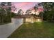 Charming single-story home at sunset with a manicured lawn, mature trees, and long driveway at 19939 Sw 96Th Pl, Dunnellon, FL 34432