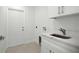 Functional laundry room with white cabinets, sink, and exterior door at 19939 Sw 96Th Pl, Dunnellon, FL 34432