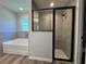 Modern bathroom showcasing a separate shower with glass doors and a luxurious soaking tub under a window at 20652 Sw Cardinal Ave, Dunnellon, FL 34431