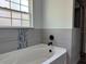 Modern bathroom features a soaking tub with matte black fixtures and stylish gray tile with mosaic accents at 20652 Sw Cardinal Ave, Dunnellon, FL 34431