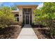 Covered front entryway with neutral colored siding and mature bushes on either side of the walkway at 21884 Sw 88Th Lane Rd, Dunnellon, FL 34431