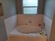 Bright bathroom featuring a deep soaking tub with tiled surround and a window for natural light at 33 Pecan Pass Trl, Ocala, FL 34472