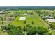 An aerial view of a horse property featuring barns, a riding arena, and several fenced pastures at 5415 Nw 100Th St, Ocala, FL 34482