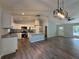 Open-concept living room boasts new flooring, modern lighting fixtures, and a kitchen with white cabinetry at 5799 Sw 207Th Ct, Dunnellon, FL 34431