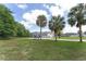 Spacious backyard features mature palm trees, expansive grass, and a long driveway leading to a detached garage on a sunny day at 5819 Ne 72Nd St, Silver Springs, FL 34488