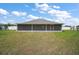 View of the home's back exterior featuring a screened-in patio and a sprawling lawn at 6292 Se 13Th St, Ocala, FL 34472