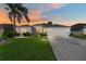 Charming single-story home with manicured lawn, mature palm tree, and two-car garage, bathed in the warm glow of sunset at 680 Farmington Ave, The Villages, FL 32162