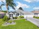 Beautiful single-story home with a well-manicured lawn, lush landscaping, and a spacious driveway at 680 Farmington Ave, The Villages, FL 32162