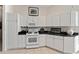 White kitchen features ample cabinetry and stainless steel appliances at 680 Farmington Ave, The Villages, FL 32162