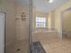 An elegant bathroom features a glass shower and a soaking tub beneath a bright window at 7370 Sw 129Th Ln, Ocala, FL 34473