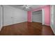 Bedroom featuring laminate floors, ceiling fan, and closet with pink accent wall at 7370 Sw 129Th Ln, Ocala, FL 34473