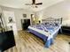 Comfortable bedroom features wood-look floors, a ceiling fan, and a blue and white quilt at 7474 Se 172Nd Fieldcrest St, The Villages, FL 32162