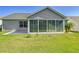 Back exterior featuring an enclosed sunroom that adds living space, surrounded by lush grass at 7474 Se 172Nd Fieldcrest St, The Villages, FL 32162