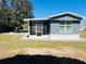 Charming home exterior with blue siding, screened porch, and well-maintained lawn on a sunny day at 9247 Se 142Nd Pl, Summerfield, FL 34491