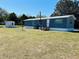 Home exterior featuring blue siding, metal roof, and a small storage shed in a grassy yard at 9247 Se 142Nd Pl, Summerfield, FL 34491