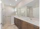 Bright bathroom featuring double sinks with dark wood cabinets and a walk-in shower with glass door at 9697 Sw 102Nd Ter, Ocala, FL 34481