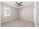 This bedroom features a ceiling fan, neutral paint and carpet, and a window overlooking the property at 9697 Sw 102Nd Ter, Ocala, FL 34481