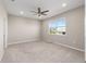 This bedroom features a ceiling fan, neutral paint and carpet, and a window overlooking the property at 9697 Sw 102Nd Ter, Ocala, FL 34481