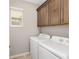 Well-lit laundry room with overhead cabinets and a modern, front-loading washer and dryer set at 9697 Sw 102Nd Ter, Ocala, FL 34481