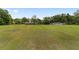 Wide open lawn with a few buildings in the distance and trees surrounding the perimeter at 10575 Sw 27Th Ave, Ocala, FL 34476